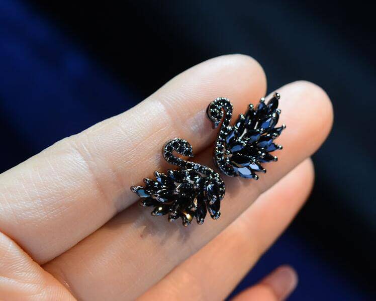 Swan Crystal Earrings showcased in a hand, featuring sparkling stones and an elegant swan design.